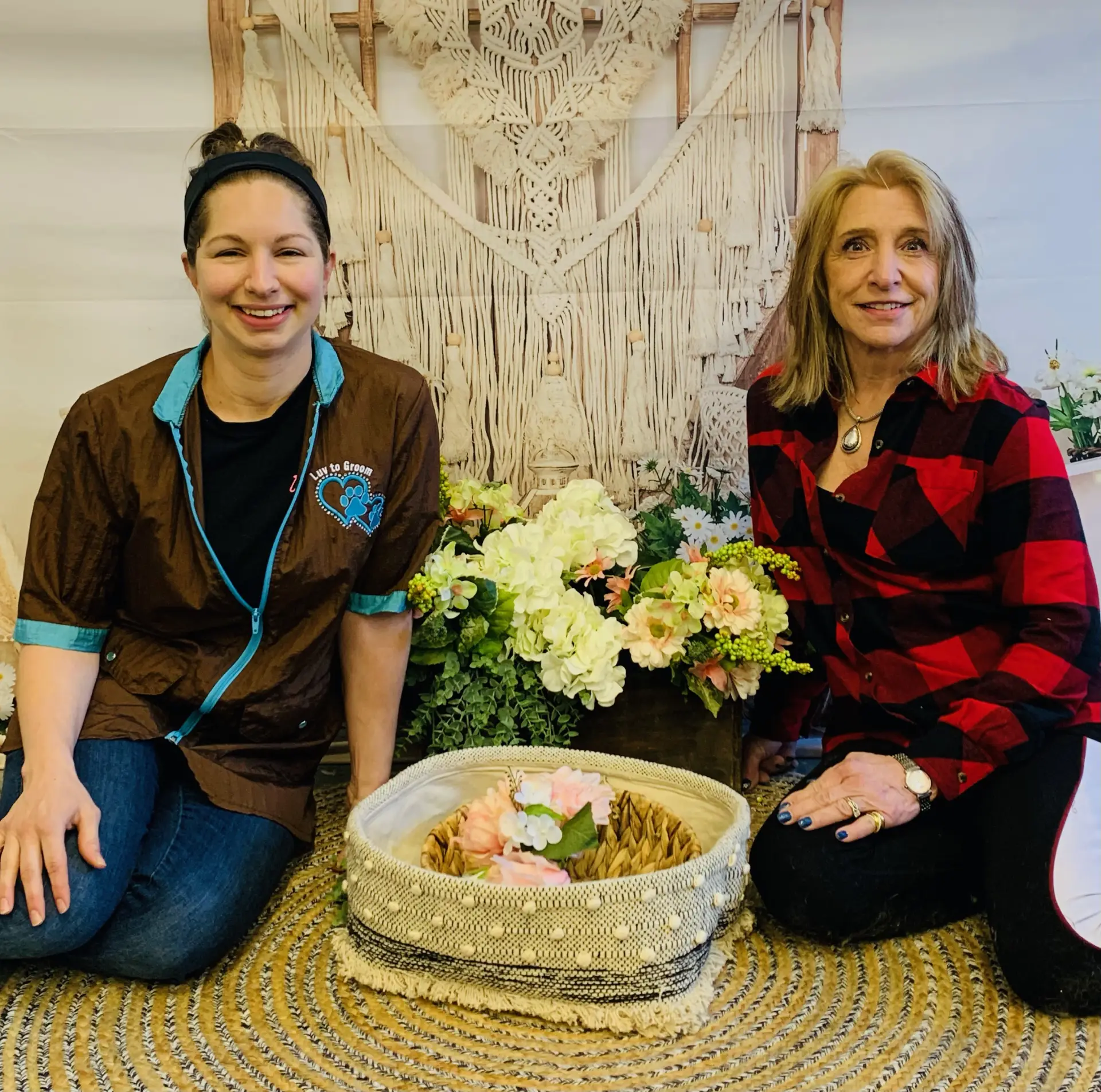 two women sitting with a flower pot in between